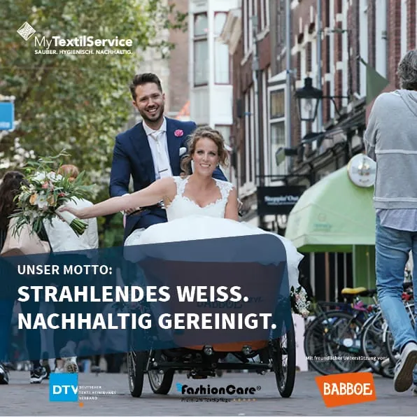 Braut sitzt in Lastenfahrrad, Bräutigam fährt.