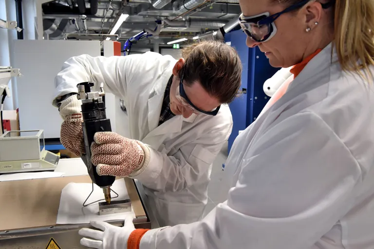 Forscher bef&uuml;llt Rakel mit geschmolzenem PHA mit einer Hei&szlig;klebepistole.