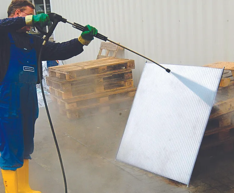 Mann reinigt Drainageplatte mit Hochdruckreiniger.