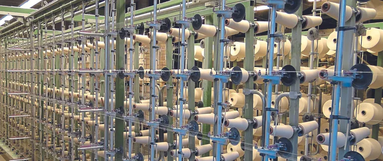 Garne und Spulen im Vorwerk der Produktionshalle der DAMINO GmbH.