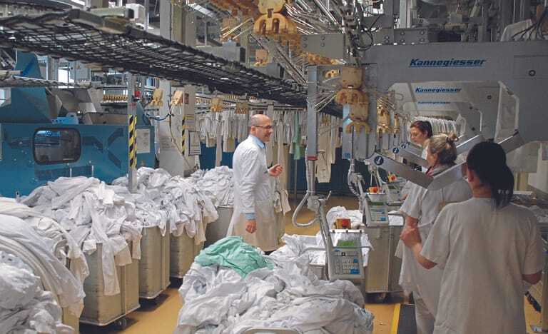 Samuel Bigot, Leiter der Wäscherei an der Uniklinik Freiburg, beim Gespräch mit Mitarbeiterinnen in der Produktion.