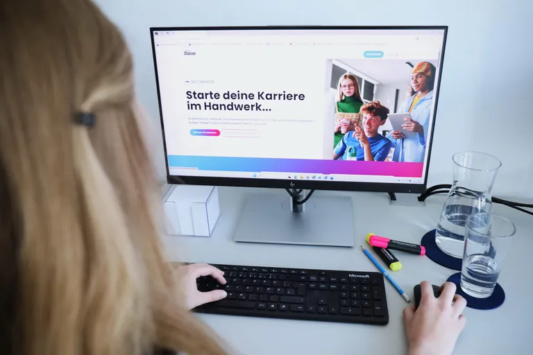 Junges M&auml;dchen sitzt am Schreibtisch vor einem PC und hat die Website "130 Chancen" der Handwerkskammer Region Stuttgart ge&ouml;ffnet.