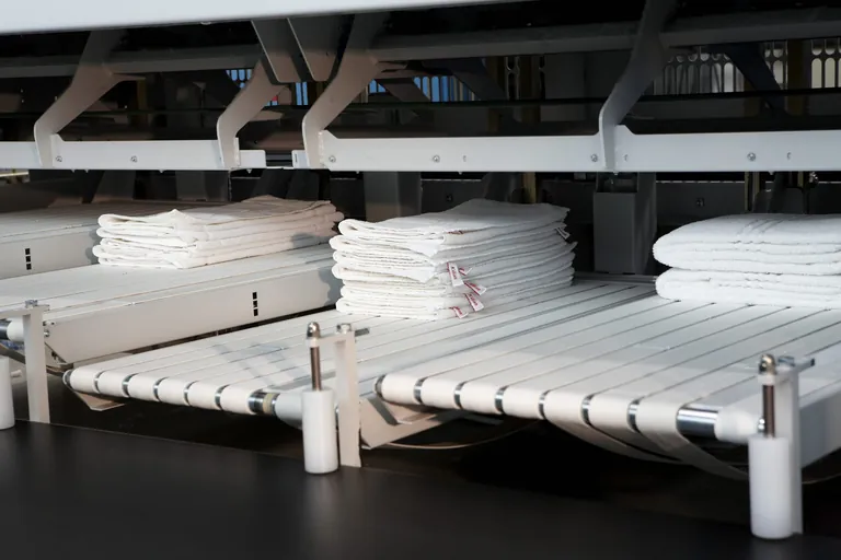 Foto von Stapeln an Frotteehandt&uuml;chern auf einer Legemaschine bei Floringo.