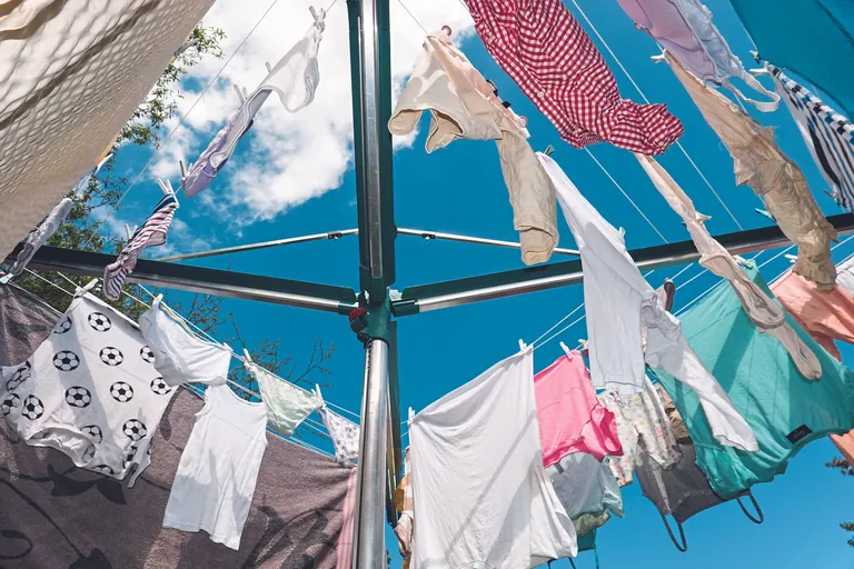 Wäsche trocknet im Freien auf einer Wäschespinne - Blick von unten.