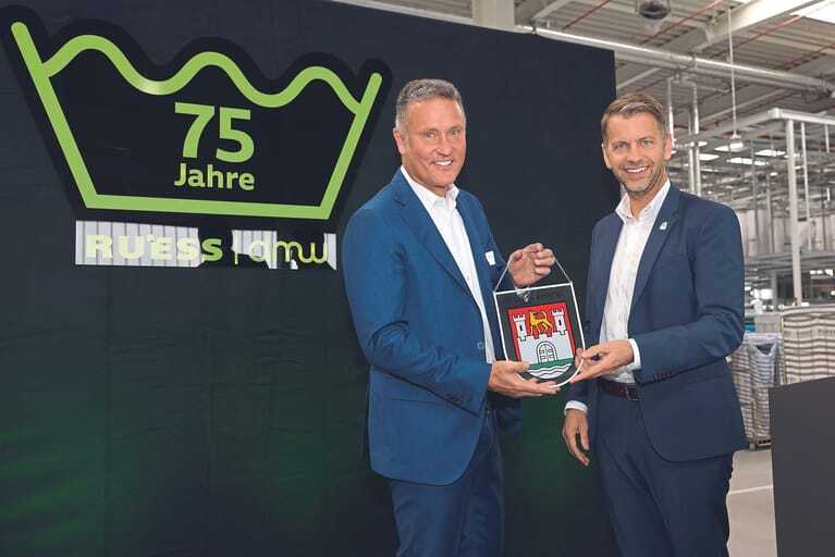 Anl&auml;sslich des 75. Firmenjubil&auml;ums &uuml;bergibt Oberb&uuml;rgermeister Dennis Weilmann (re.) das Glaswappen der Stadt Wolfsburg an Henrik Rue&szlig;.