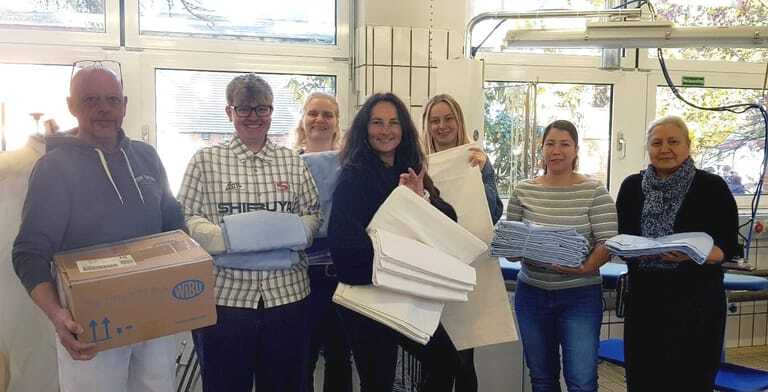 Bei der Wäscheübergabe (v.li.): Holger Wilhelm/ Segeberger Kliniken GmbH in Schleswig-Holstein, Lea Fischer/ Mewa Textilservice in Lauenburg, Ilka Falkenau/ Lehrkraft an der Theodor-Litt-Schule, Ellen Kemper/ Lehrkraft an der Theodor-Litt-Schule, Emily Loeck/ Wäscherei Exner in Hamburg, Valeria Restrepo Delgado/ Wäscherei Schwarting aus Niedersachsen/ Diakonie Nord-Nord-Ost in Lübeck, Alsinia Khabibullina/ Diakonie Nord-Nord-Ost.