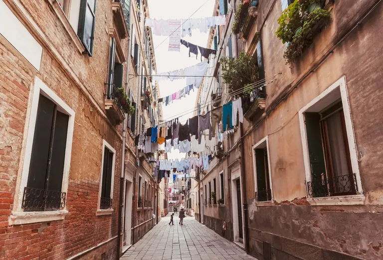 Zwischen ihre H&auml;user spannen Venezianer W&auml;scheleinen. Diese laufen &uuml;ber Rollen. W&auml;sche l&auml;sst sich so leicht von Fenster aus aufh&auml;ngen.