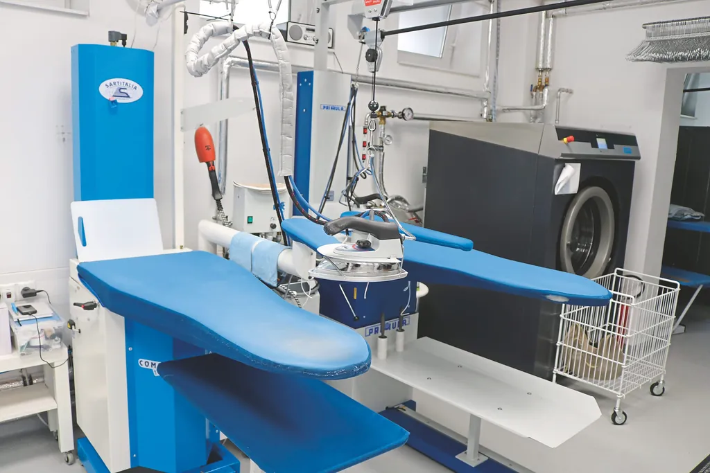 An den B&uuml;geltischen werden die Kleidungsst&uuml;cke von Hand &shy;geb&uuml;gelt und kontrolliert.