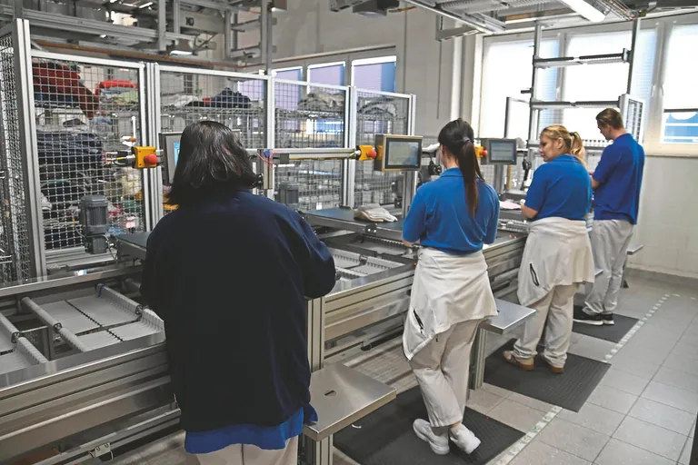 Die gelegte Kleidung wird in einer Sortiermaschine, die 220 Kisten umfasst, automatisch nach einzelnen Bewohnern kommissioniert.