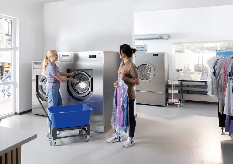 Zwei Frauen waschen Wäsche in einer Miele Waschmaschine. Eine Einstimmung auf die EXPOdetergo 2026.
