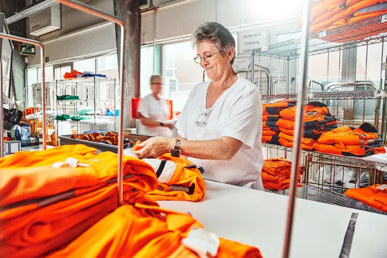 Eine Elis-Mitarbeiterin sortiert die gereinigte, gepflegte Arbeitsbekleidung.