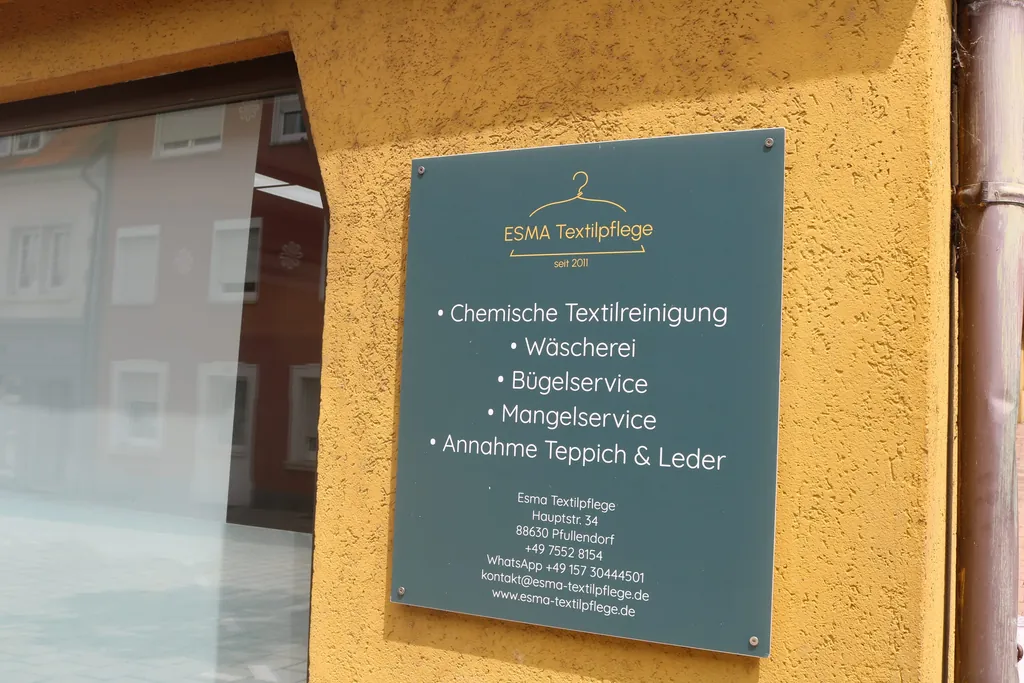 Von Wäscherei bis Bügelservice: Ein Schild an der Hausfassade informiert über die Leistungen.