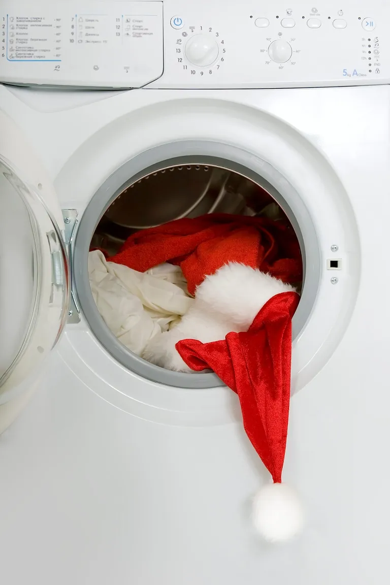Eine Weihnachtsmannmütze ragt aus einer Waschmaschine heraus.